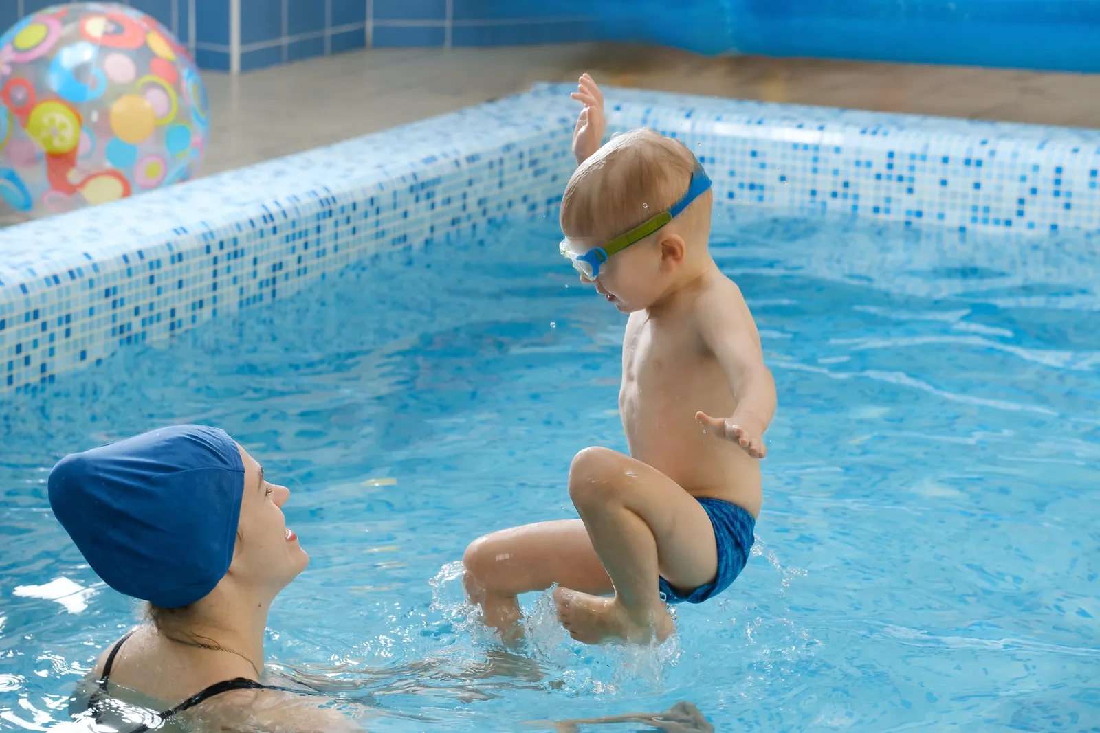 Jong kind springt vanaf de badrand naar een instructeur in het water