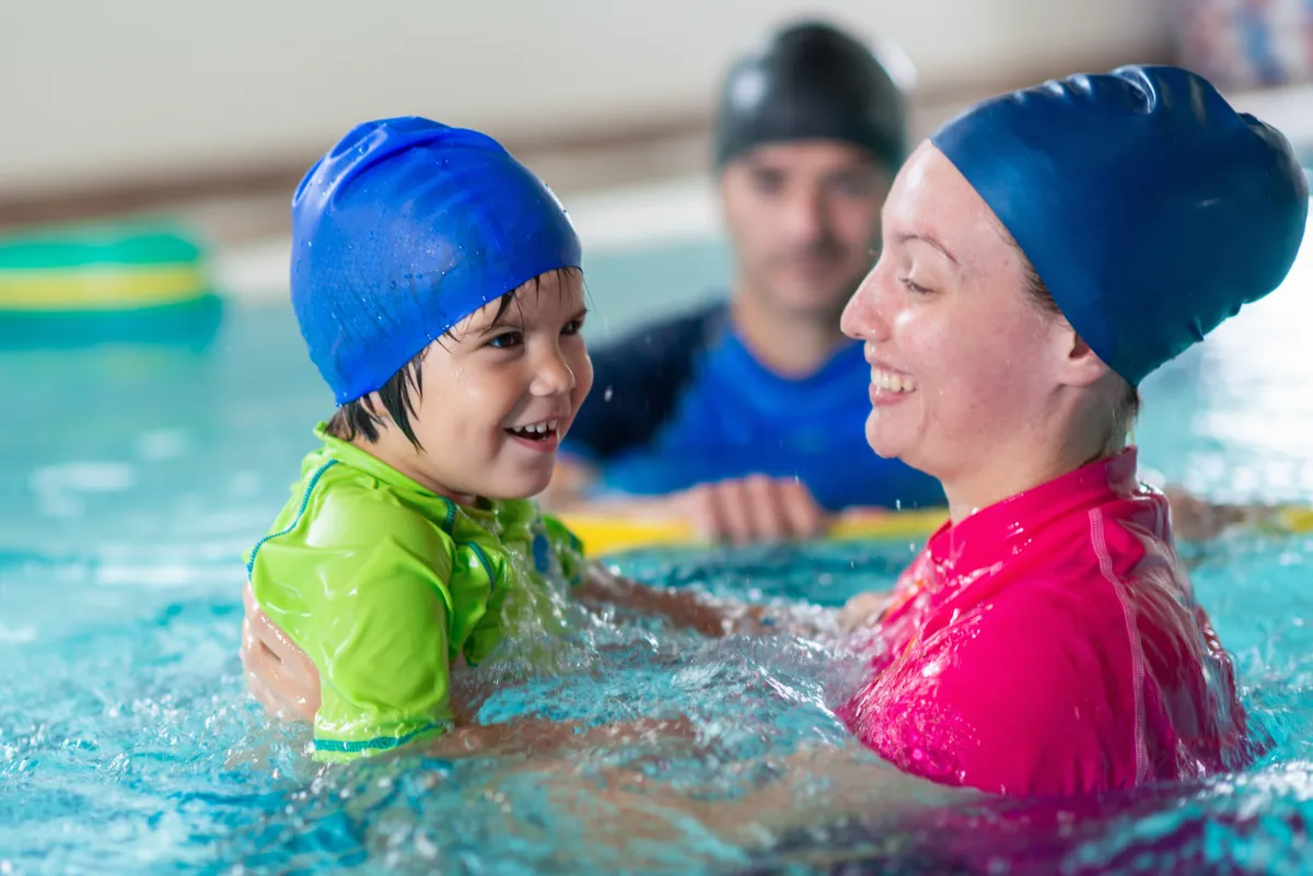 Instructeur en jong kind in het water tijdens een zwemles